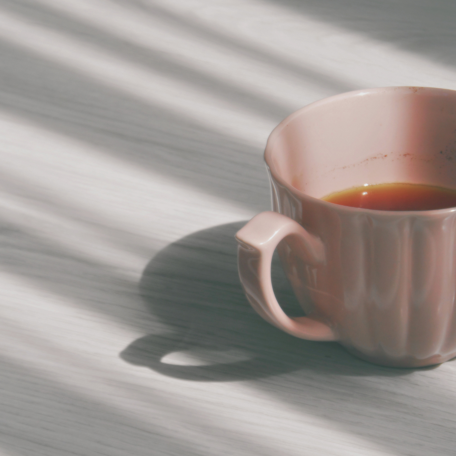 Delicate pink teacup with tea on a sunlit table – warm and quiet moments crafted with thoughtful tableware design